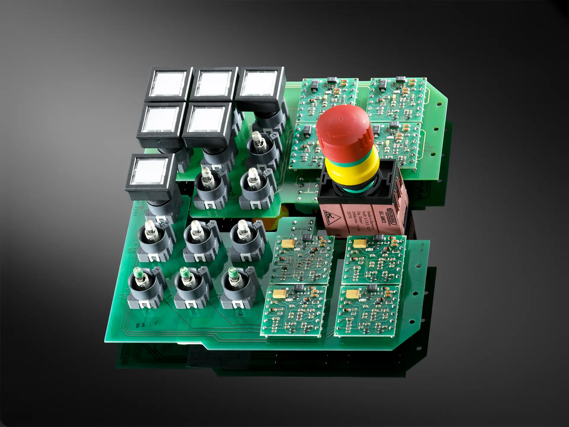 Eine grüne Platine mit einem Not-Halt-Taster und rechteckigen Drucktastern.